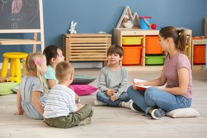 Nursery teacher with cute little children in kindergarten