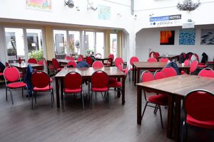 Foto von einem Saal mit vielen Stühlen und Tischen. 