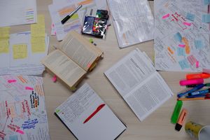 Foto von aufgeschlagenen Büchern, in denen mit bunten Textmarkern viel markiert ist.