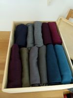 Foto von gefalteten und sortierten Kleidungsstücken, die perfekt in eine Kiste passen.