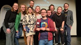 Freuen sich mit Dr. Markus Prinz über den Gewinn des Science Slam: Nathalie Kürten (IfV), Komoderatorin des Abends; Dr. Maren Bertheau (UOL); Dr. Rufina Fingerhut; Dr. Matthias Weissensteiner (IfV); Jenny Neuhaus (DZMB, Senckenberg am Meer); der Preisträger (ICBM); Dominik Antoni (AWI); Lennart Barke (Wattenmeer Besucherzentrum, hielt einen Vortrag über Wissenschaft außer Konkurrenz); Justine Bertram (IfV) und Dr. Moritz Mennenga (NIhK, Geschäftsführer NWDUG).