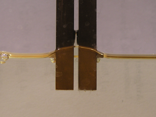 Geladene Kondensatorplatten heben Öl an. Foto von Kondensatorplatten die eine isolierende Flüssigkeit anheben.