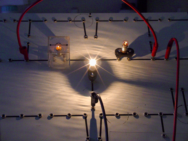 Zwei parallele Glühlampen in Reihe mit einer. Foto von zwei dunklen und einer hellen Glühlampe.