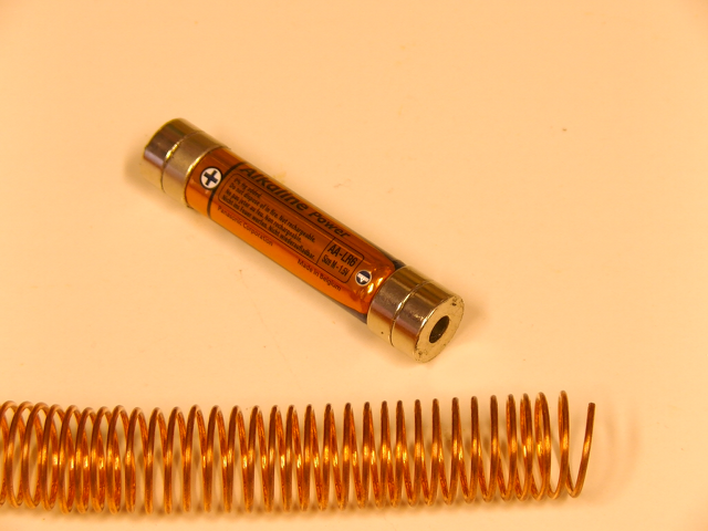Batterie mit Magneten an den Enden und Drahtspule. Foto einer Batterie mit Magneten an den Enden und Drahtspule.