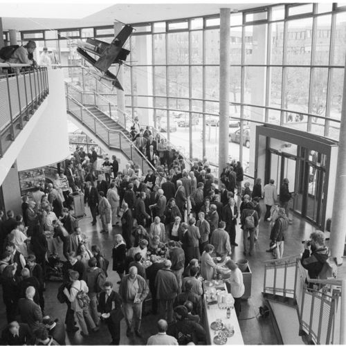 Das Bild zeigt Menschen, die am Eröffnungstag im Foyer des Audimax stehen. Ein Buffett ist aufgebaut, Fotografen fotografieren die Szene.