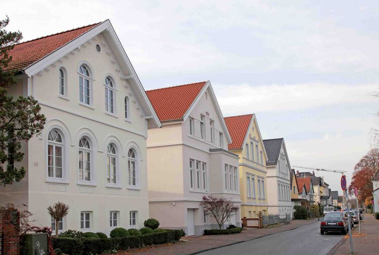 Oldenburger Hundehütten  A row of "Hundehütte"-style houses in Oldenburg with red tile roofs and well-maintained gardens.