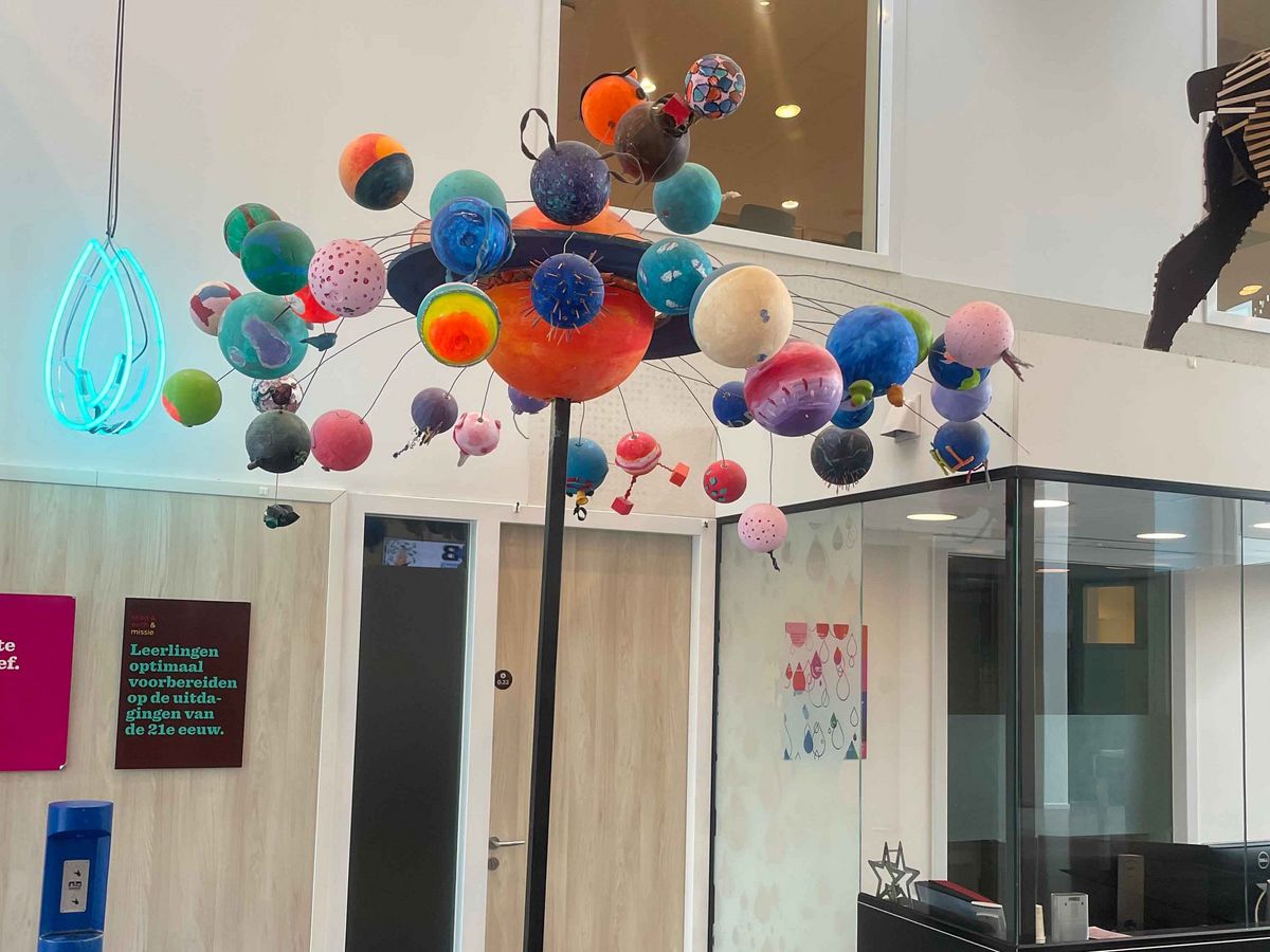 Teaching Across Borders Eine Installation mit planetarischen Modellen von der Decke. Im Hintergrund ist ein Empfangsbereich.