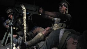 Das Bild zeigt eine Soldaten-Wachsfigur, die ein Maschinengewehr abfeuert. Um die Figur sind weitere Soldaten drapiert, offenbar ist mindestens einer von ihnen tot. Der MG-Schütze schaut grimmig.