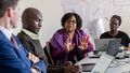 The picture shows a discussion taking place during a colloquium. An African participant is describing an issue to Professor Karsten Speck from the University of Oldenburg. The other participants watch and listen.