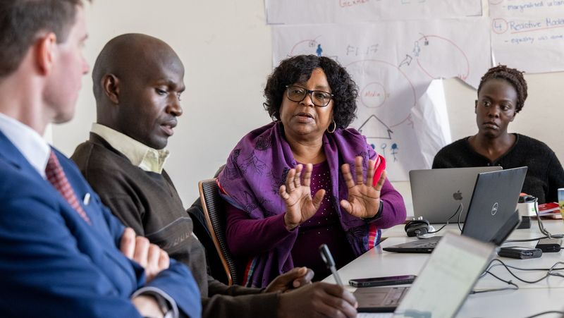Das Bild zeigt eine Diskussion in einem Kolloquium. Eine afrikanische Teilnehmerin schildert dem Oldenburger Professor Karsten Speck einen Sachverhalt. Weitere Teilnehmende schauen und hören zu.
