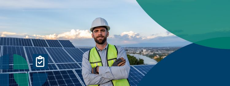 Ein Mann in Warnweste steht mit verschränkten Armen vor Solaranlagen auf einem Dach.
