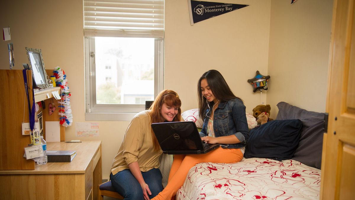 CSUMB Wohnheimzimmer mit zwei Studierenden, die sich über einen Laptop beugen
