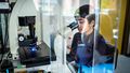 Young woman looking into the eyepiece of a microscope.