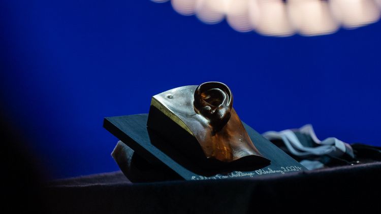The award is in the shape of a golden ear with a neighbouring face.