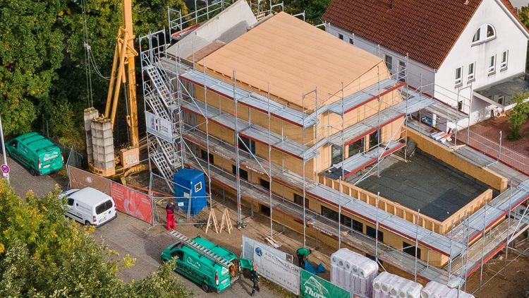 Luftbild des Gebäudes, das von Gerüsten, Containern und einem Kran umgeben ist.