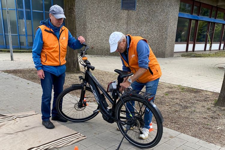 Zwei Personen beugen sich über ein Fahrrad. Eine Person hat ein Gerät zum Codieren in der Hand. Die beiden Menschen tragen ADFC-Westen.