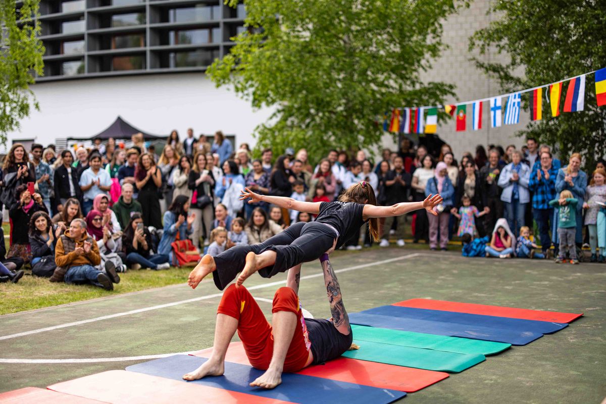 Acro Yoga Vorstellung mit begeistertem Publikum im Hintergrund.