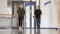 Two women wearing masks walk through the foyer of the lecture hall building A14.