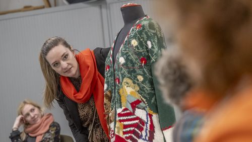 Eine wild gemusterte Strickjacke hängt über einer Art Schaufensterpuppe, dahinter schaut Klara von Lindern hervor. 