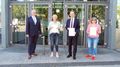 Four people stand in front of the entrance of the lecture hall.