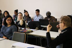 Lehrperson, rechts, im Gespräch mit Studierenden