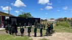 Praktikum im Ausland  Eine Gruppe von Schulkindern in grünen Uniformen, die im Freien im Kreis stehen und von einer Frau in schwarzer Kleidung angeleitet werden.