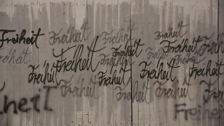 Das Wort Freiheit ist in unterschiedlichen Farben und Schriften auf eine Wand gemalt.