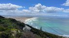 Küste Eine Panoramansicht auf eine Küstenlandschaft mit grünen Hügeln, einem langen Sandstrand und dem türkisfarbenen Meer.