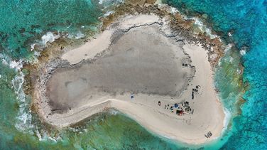 Luftbild von Latham Island: Ein kartoffelförmiges Stück Land, umgeben von türkisfarbenem Meer.