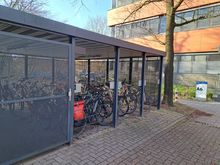 Ein Foto von dem überdachtem Fahrradunterstand Fahrrad vor dem A6 Gebäude. Im Fahrradunterstand befindet sich eine Lademöglichkeit.