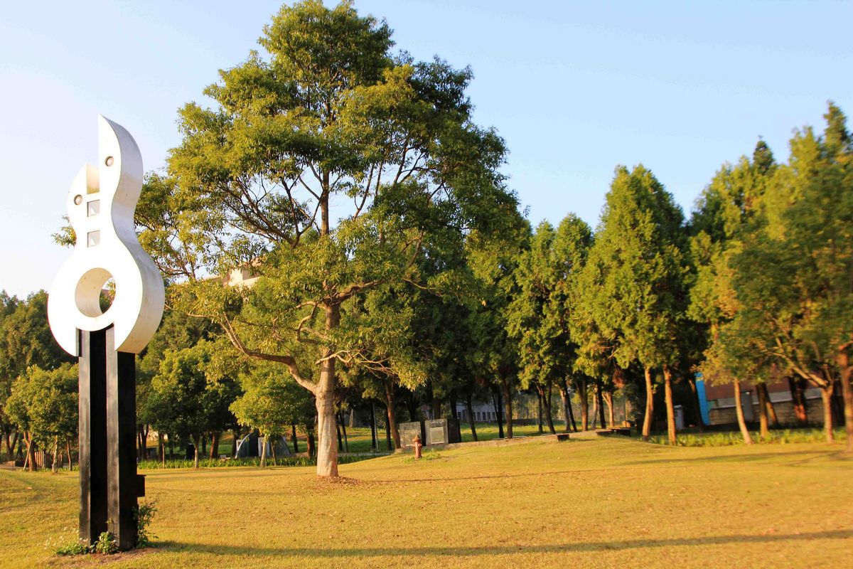 Das Bild zeigt eine moderne Skulptur vor dem Hintergrund der grünen Parklandschaft des Campus der National Chi Nan University an einem sonnigen Tag.