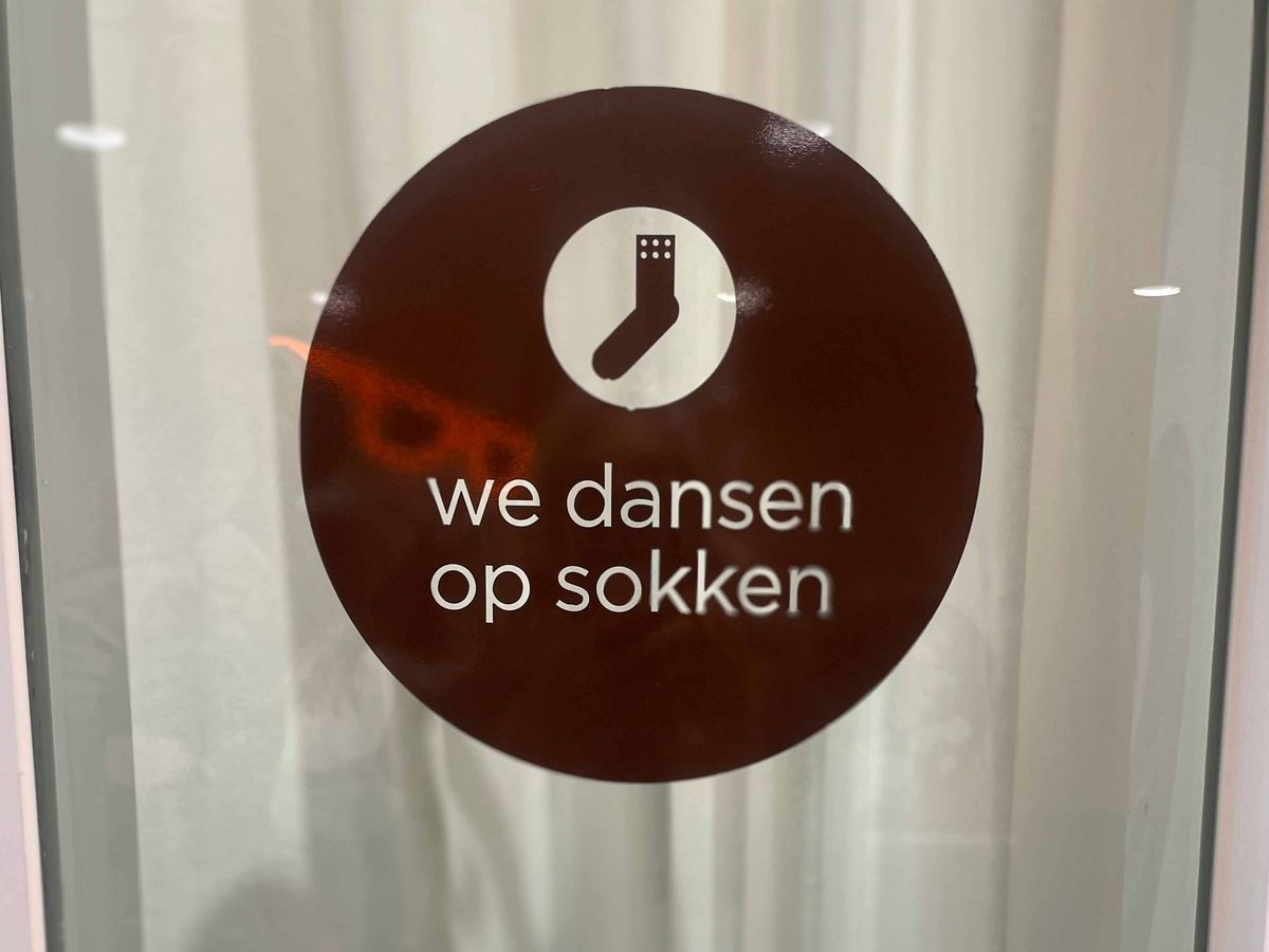 Teaching Across Borders Ein Schild mit einem weißen Sockensymbol und dem Text "we dansen op sokken".