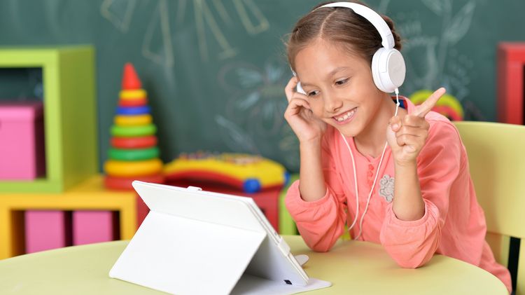 Kind im Klassenzimmer mit Tablet und Kopfhörern.