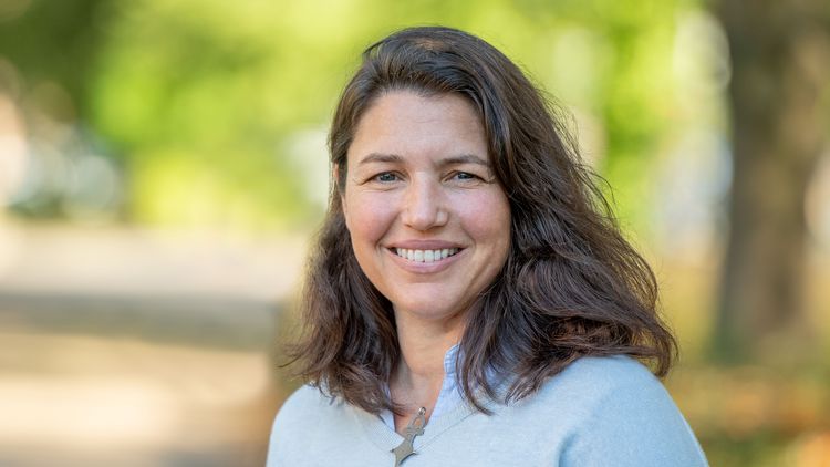 Portrait von Iliana Baums vor verschwommenem, sonnigen Hintergrund.