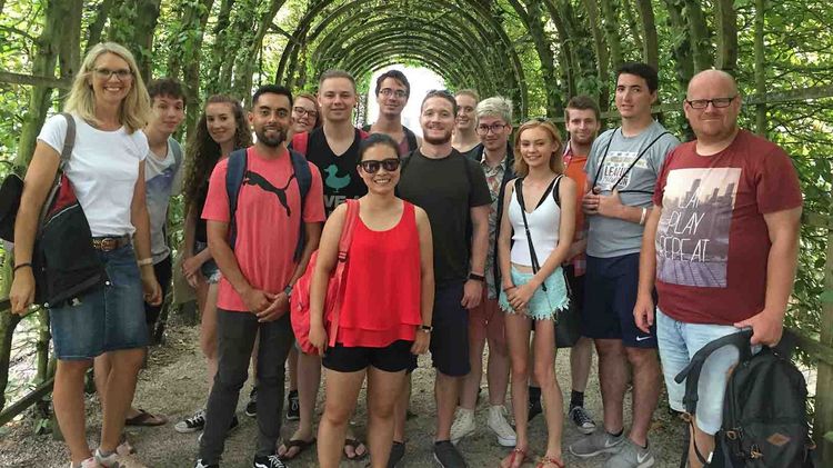Exkursion Eine Gruppe von Menschen in einem grünen Tunnel aus Pflanzen.