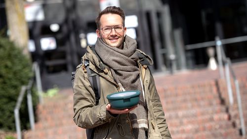Man in front of the canteen with a takeaway bowl 