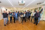 Eine Gruppe von Menschen hebt die Arme und jubelt in die Kamera.