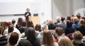 Lecture hall situation, a woman gives a presentation to a larger audience.