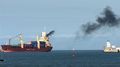 Cargo vessel emitting black exhaust gases to the air.