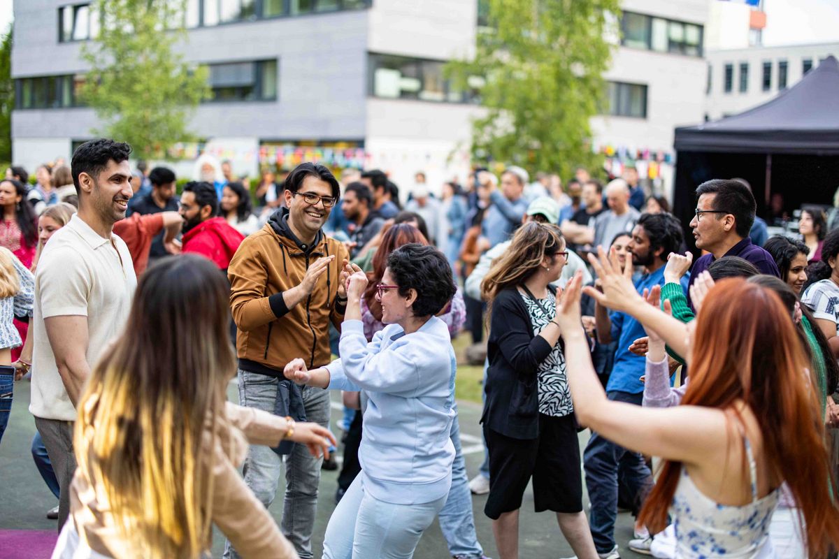 Tanzende Zuschauer*innen auf dem Sommerfest, die freudig durch die Stimmung inspiriert sind.