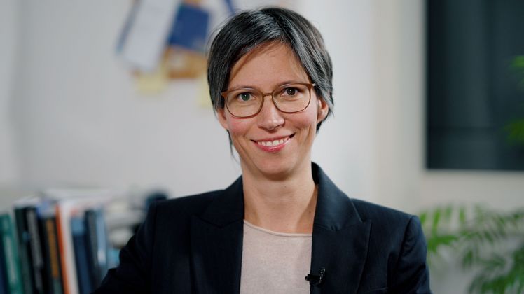 Das Bild zeigt Jannika Mattes. Sie lächelt in die Kamera. Im Hintergrund sind einige Bücher zu erkennen.