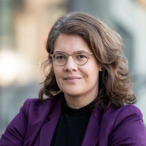 Porträt von Prof. Dr. Sina Farzin, die einen lila Blazer und ein schwarzes Oberteil trägt. Sie trägt Brille und hat braunes, schulterlanges, gelocktes Haar. Sie lächelt leicht mit geschlossenem Mund. 