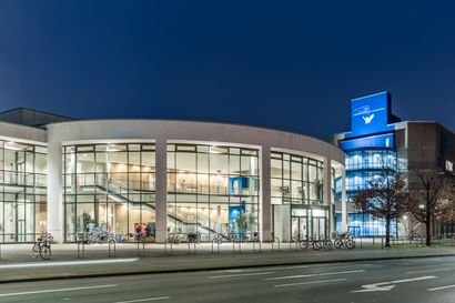 Hörsaalzentrum bei Nacht erleuchtete Glasfassade und Turm mit Uni-Logo