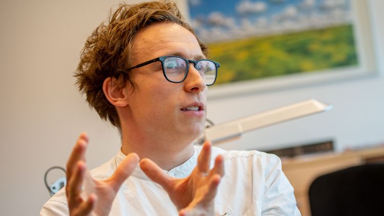 Niklas Ellerich-Groppe im Gespräch. Er gestikuliert mit den Händen, trägt eine Brille und ein weißes Hemd.