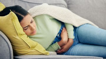 Woman with abdominal pain on the sofa.
