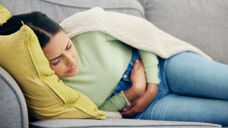 Woman with abdominal pain on the sofa.