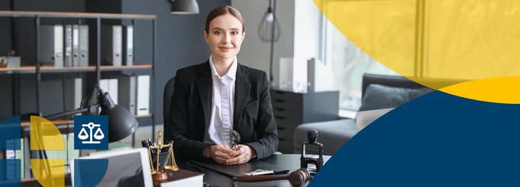 Eine Frau im Anzug sitzt in einem Büro und lächelt in die Kamera.
