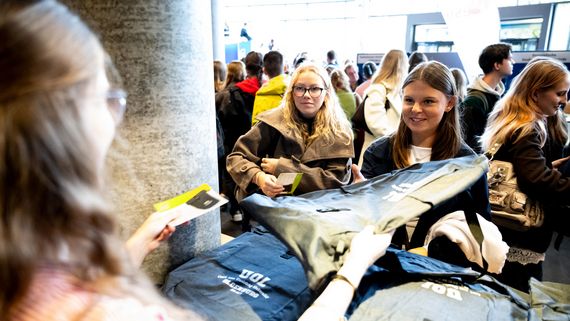 Das Bild zeigt Erstsemester, die ihre Rucksäcke von freundlichen Mitarbeitenden der Presse & Kommunikation überreicht bekommen.