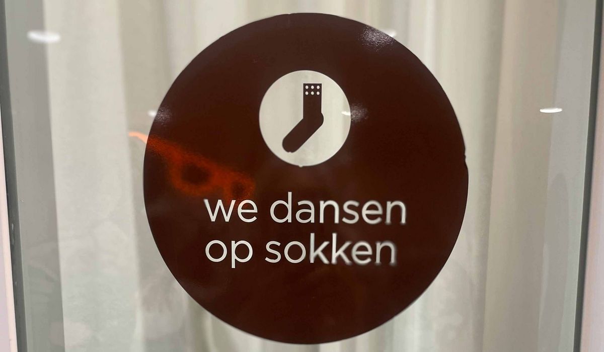 Teaching Across Borders A sign with a white sock symbol and the text "we dansen op sokken".