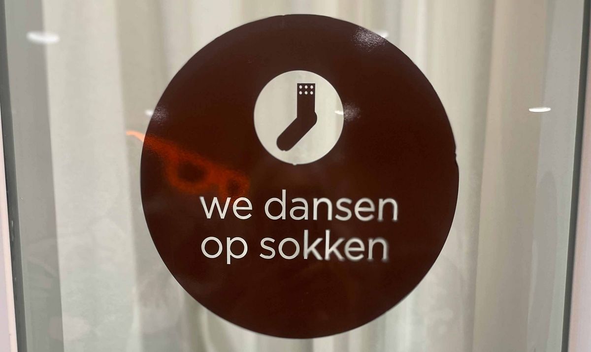 Teaching Across Borders Ein Schild mit einem weißen Sockensymbol und dem Text "we dansen op sokken".